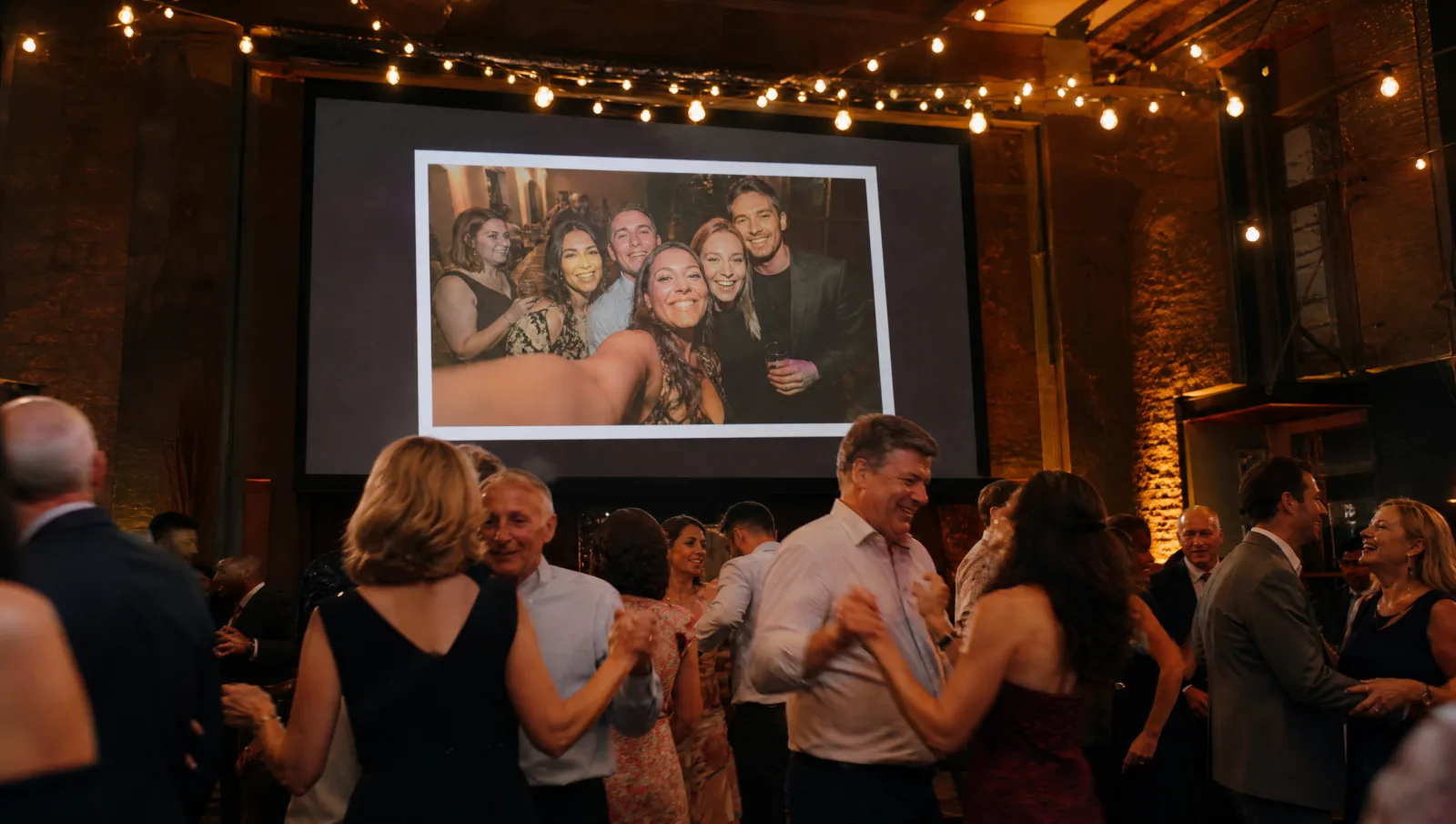 Guest photos shown on a big screen during the party
